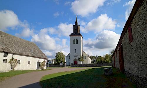 Kastlösa kyrka med prästgårdens lador Foto: Stefan Svenaeus 2022